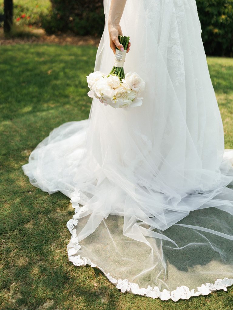 Macro shot of elegant tulle veil with delicate floral lace edge resting on green grass