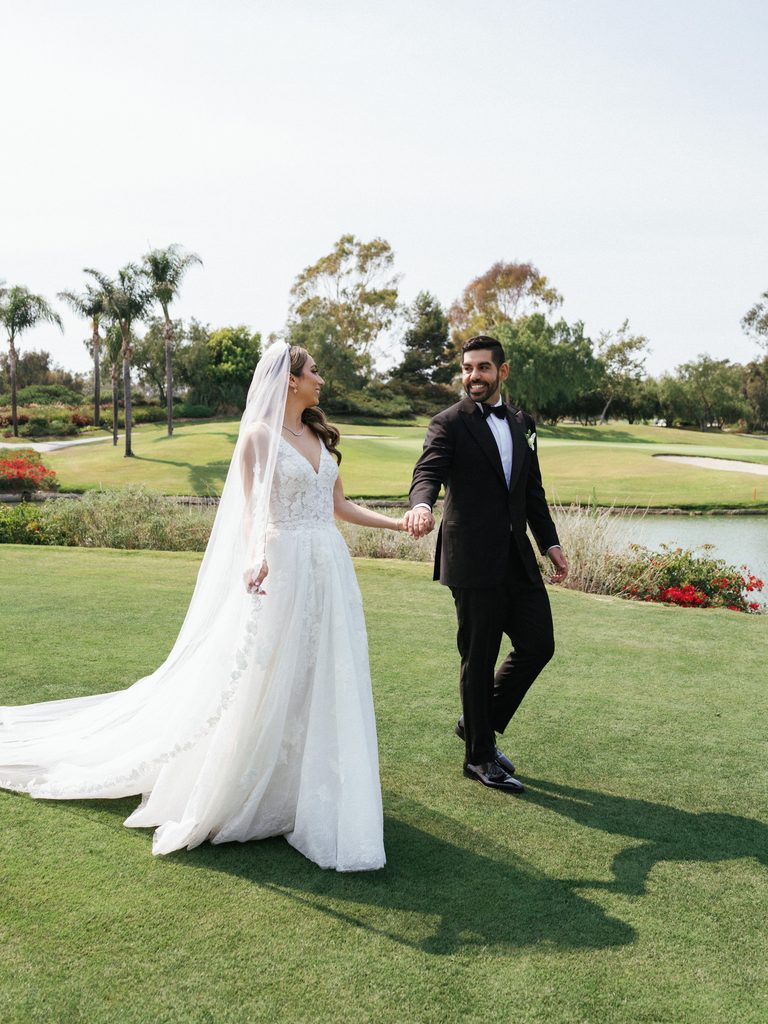 Stunning bride in A line gown looking at her husband during sunny outdoor photoshoot