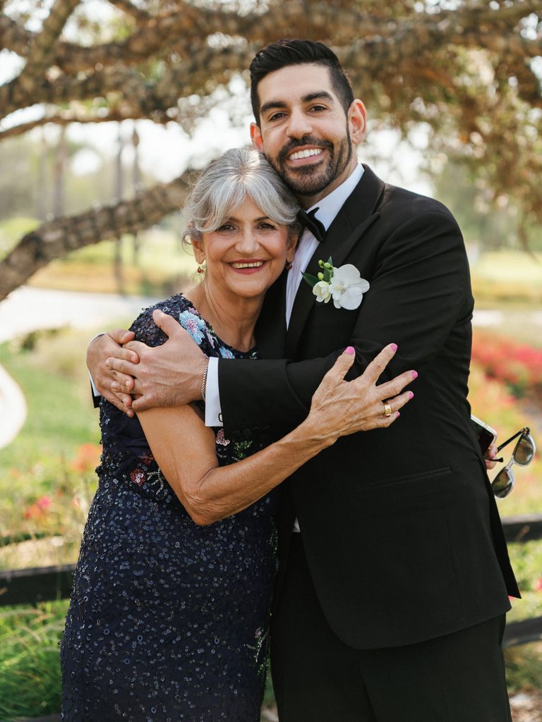 Loving mother of the groom holding her son arm with deep affection on his wedding day