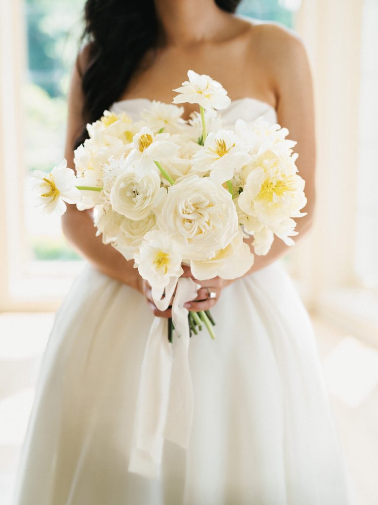 Close up wedding bouquet with white garden roses sweet peas and silk ribbon