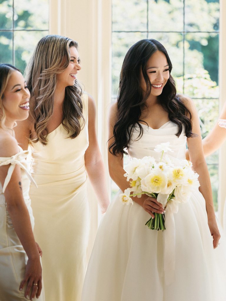 Beautiful bride in strapless gown surrounded by supportive bridesmaids during wedding morning