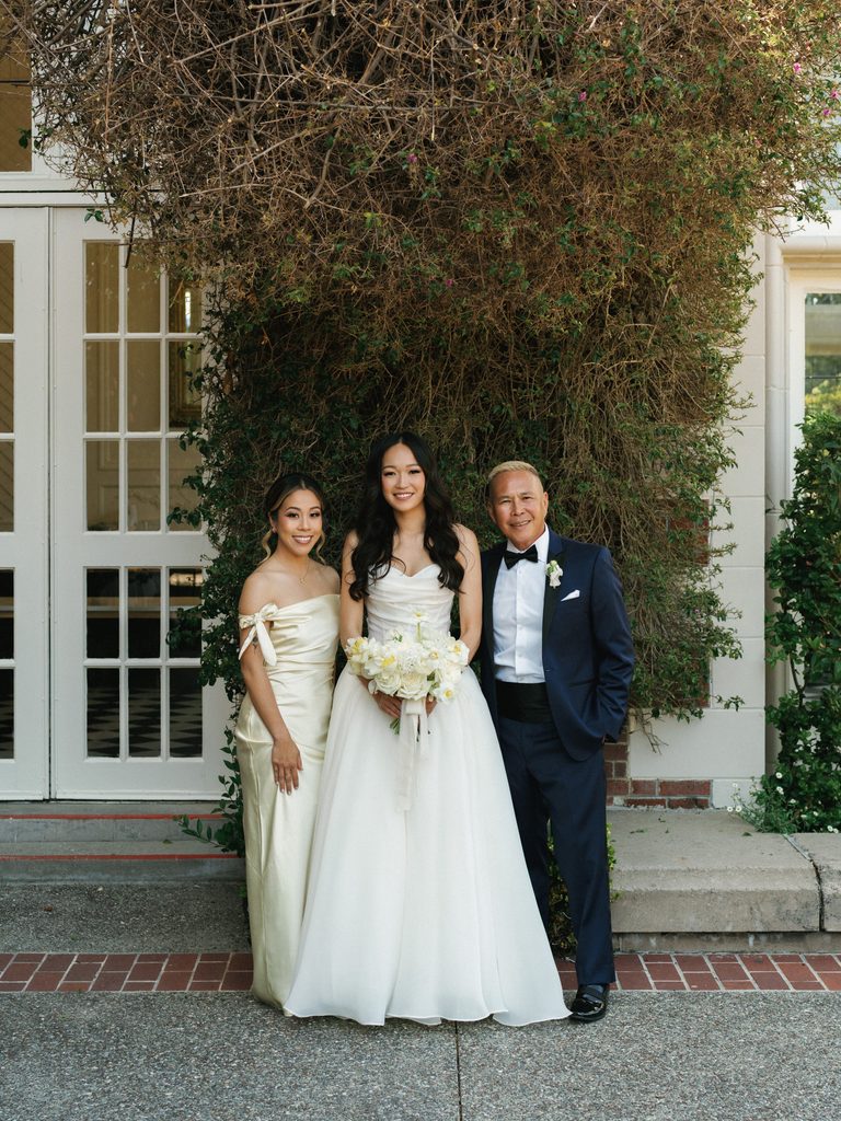 Lovely bridal party portrait outdoors near green climbing plants and white windows