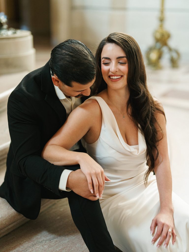Close up portrait of romantic winter wedding couple sitting on marble stairs indoor