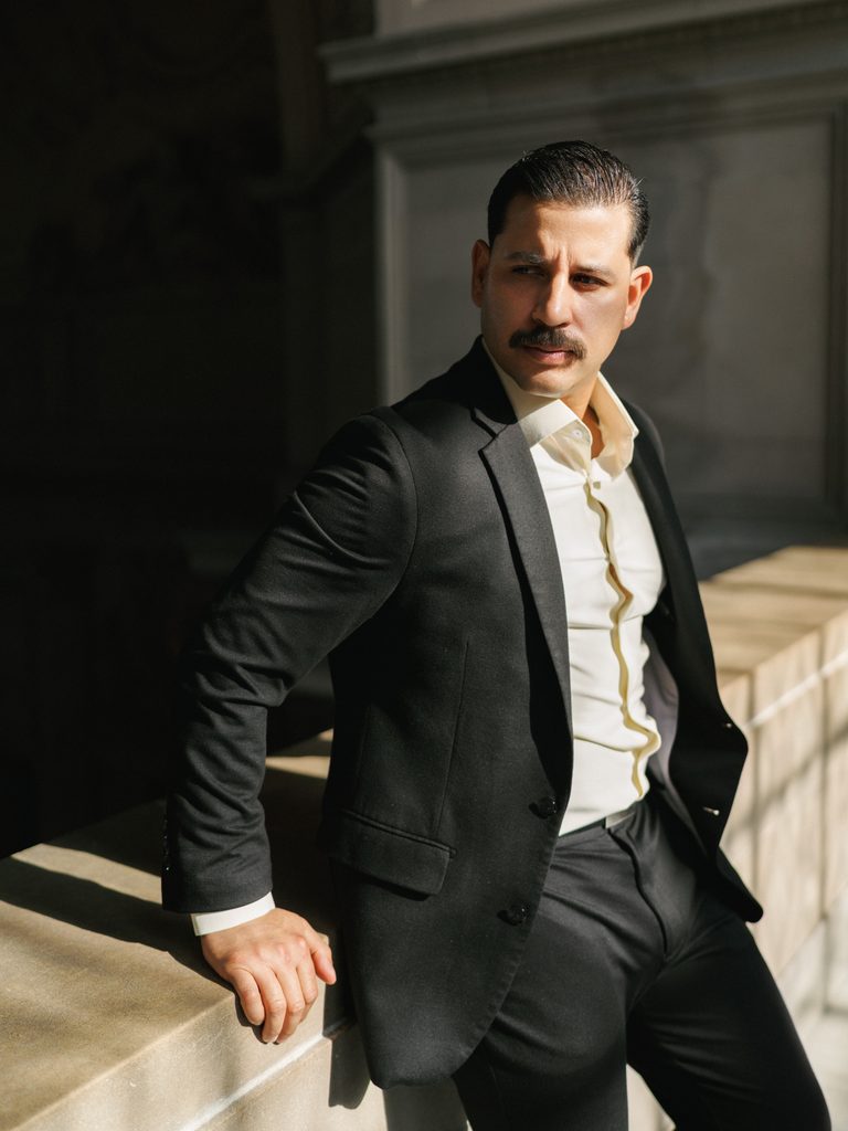 Groom in black tuxedo posing indoor during luxury California winter wedding photoshoot