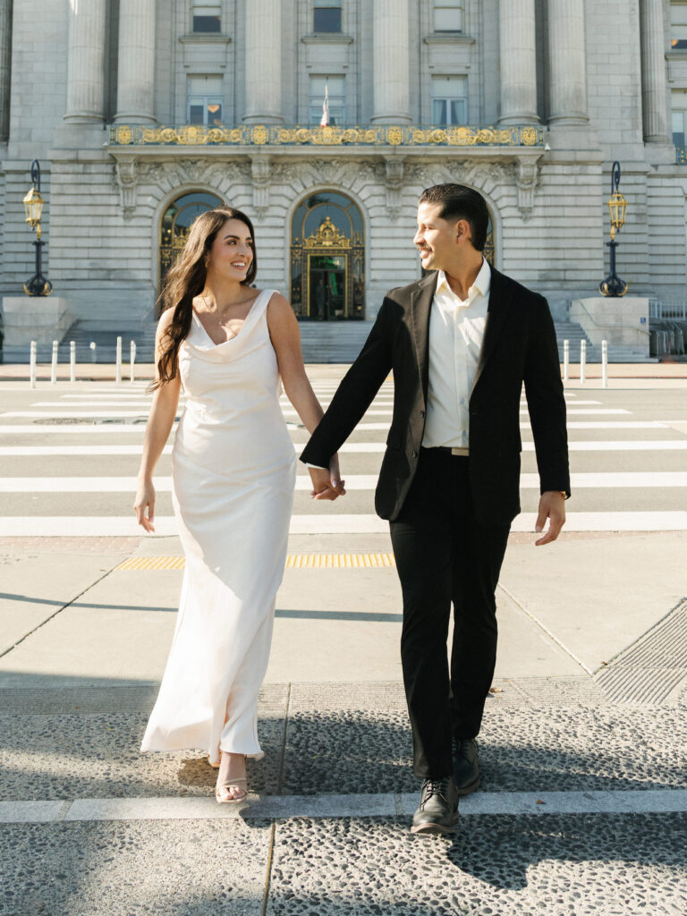Winter wedding couple holding hands and walking outdoor near San Francisco City Hall building