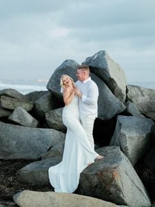 Candid newlyweds portrait at ocean shore featuring happy couple posing for blue hour wedding photos