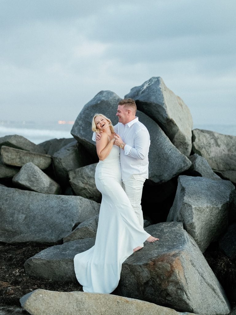 Candid newlyweds portrait at ocean shore featuring happy couple posing for blue hour wedding photos