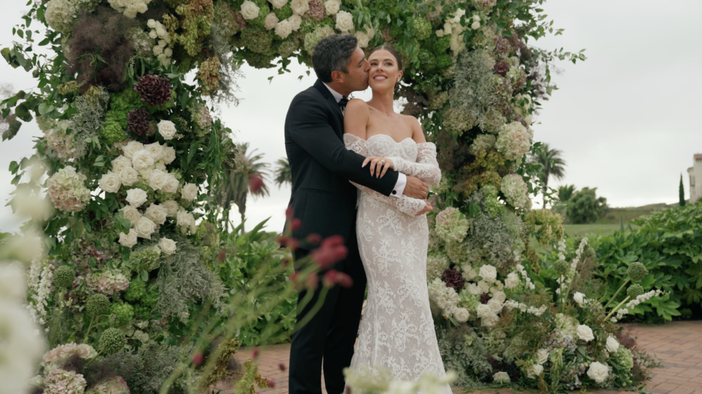 A bride and groom in front of a massive, asymmetrical floral installation. Dreamwood wedding photography with Royal Bee Flower Co.